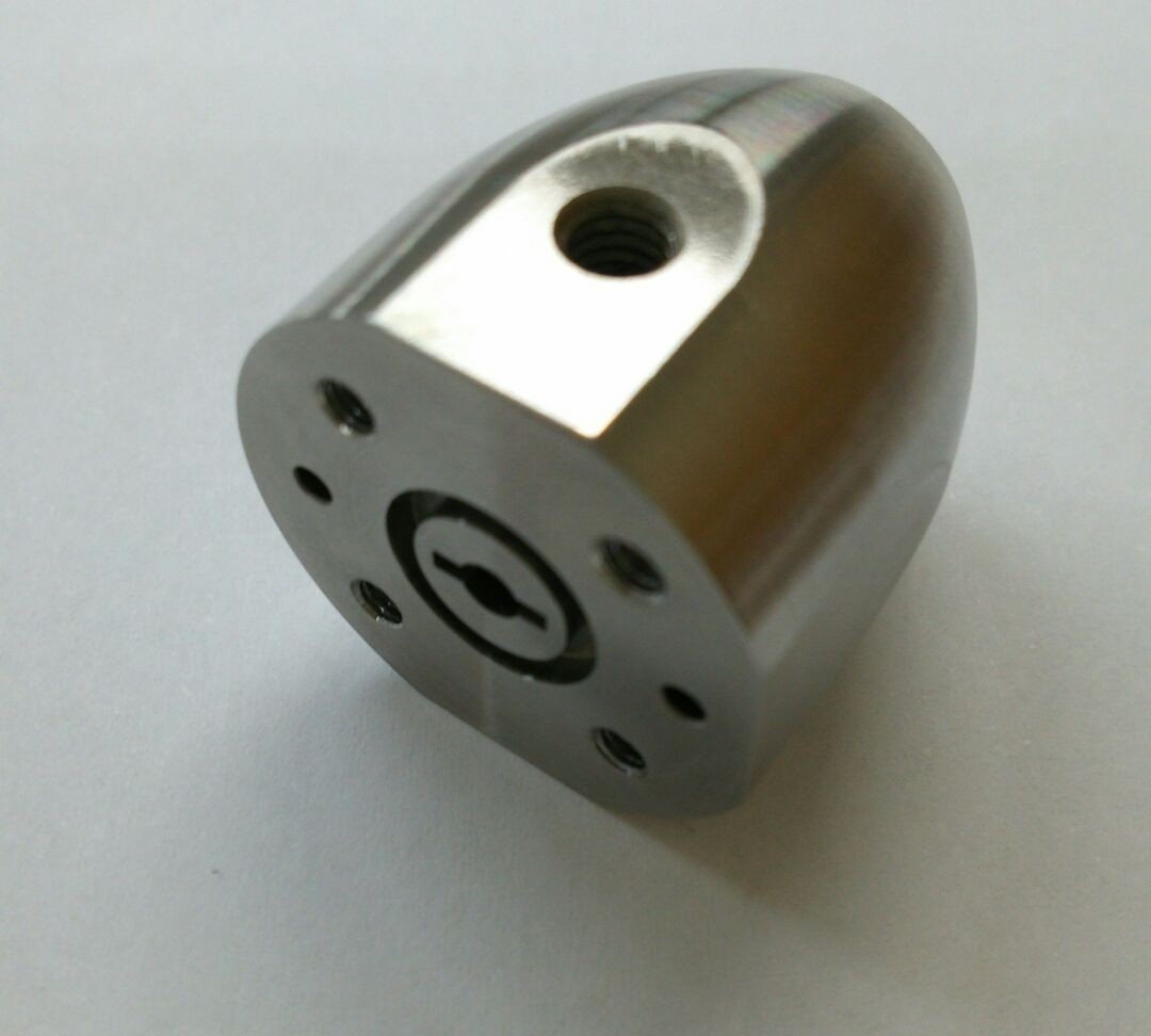 丸い金属部品の側面を平らに削り、ねじ穴を設けた小型部品。端面には小さな穴が並んでいる